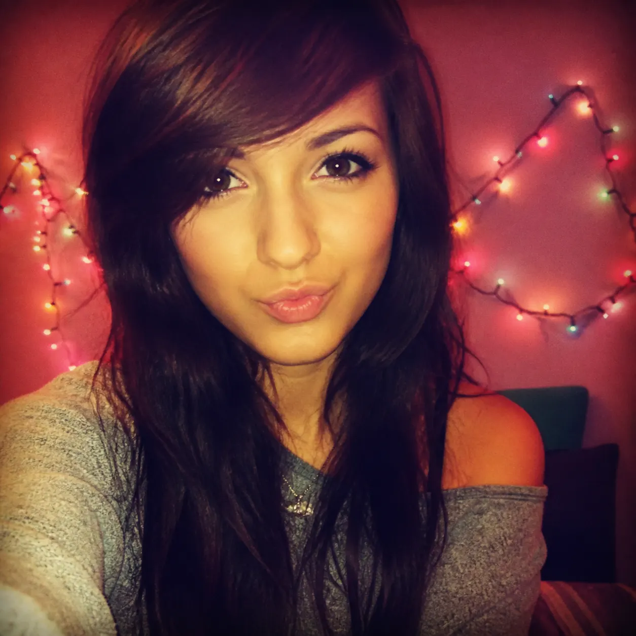 A fictional adult shown in a nostalgic square 2016-style selfie with a warm filter, side-swept hair, and colorful string lights.